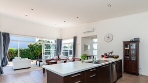 Una cucina moderna con una grande isola, mobili scuri e un'area pranzo con divano bianco e tavolo.