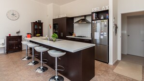 Una cucina moderna con un'isola centrale, sgabelli da bar, un frigorifero e una sveglia appesa al muro.
