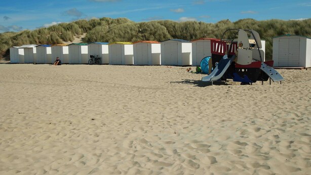 A row of beachside mobile homes with a dune in the background. - Park Atlantis (De Haan)