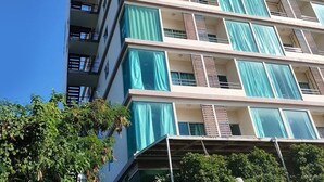 Um edifício com várias andares, varandas, janelas amplas e um céu azul límpido.