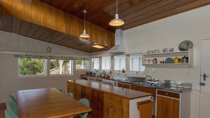 Une cuisine moderne avec des meubles en bois, un îlot central et un coin repas doté de chaises de couleur turquoise.