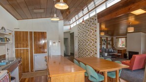 Une cuisine moderne avec des meubles en bois, un îlot central et un coin repas doté de chaises de couleur turquoise.