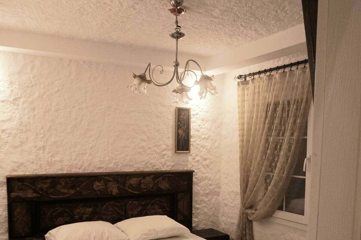 A neatly made bed with white linens, a wooden headboard, and a bedside table with a lamp.
