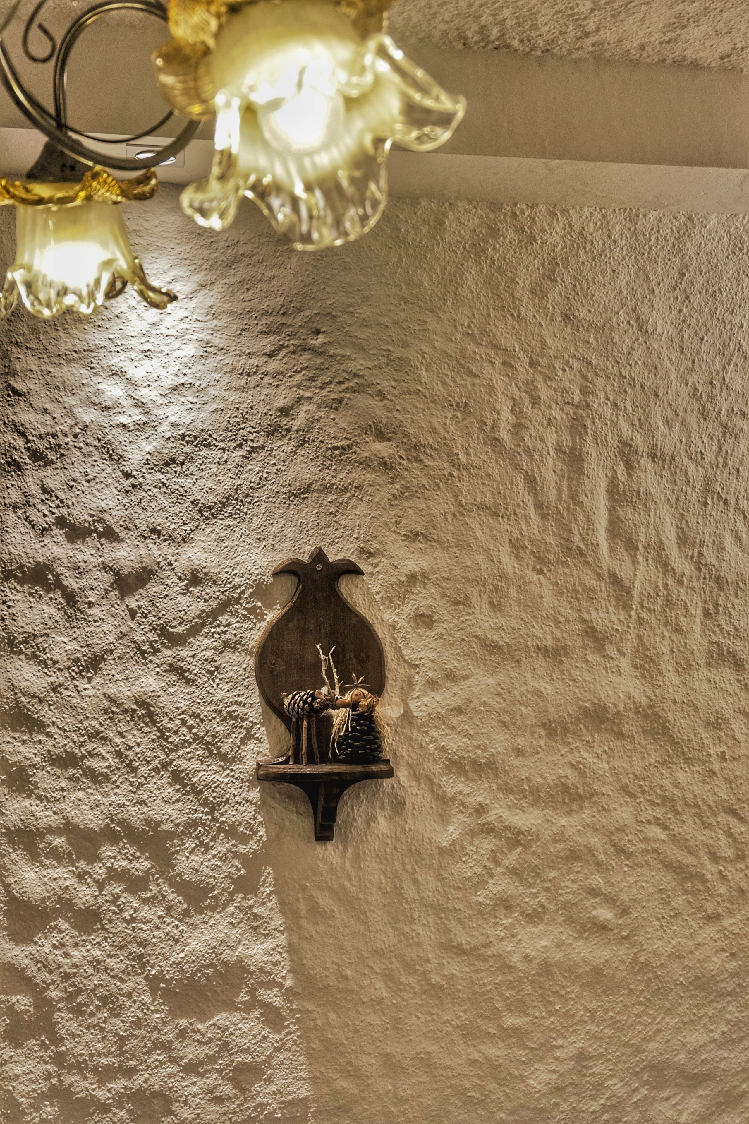 A textured wall with a wall-mounted light fixture and a decorative object.