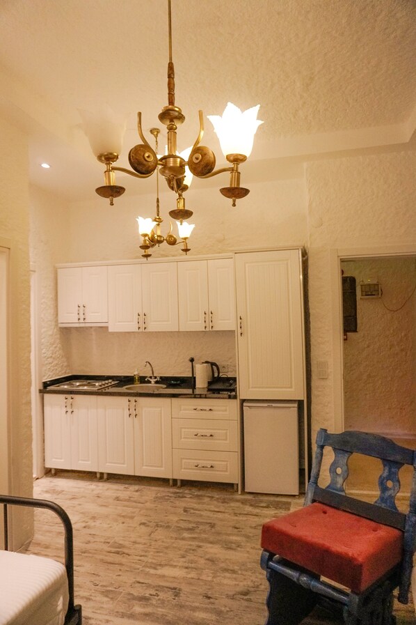 A kitchen with white cabinets, a chandelier, and a red upholstered chair.
