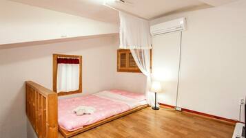 A single bedroom with a wooden bed, a bedside table, a lamp, and a window with curtains.