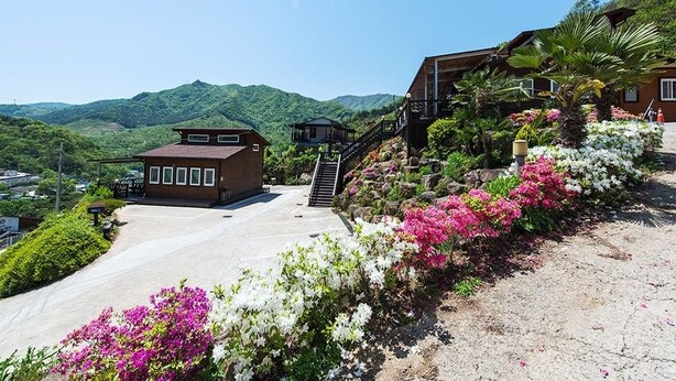 A hotel with a mountain view, a small building with a red roof, and a staircase leading to a wooden deck. - Jirisan Shiri Pension (Gurye)