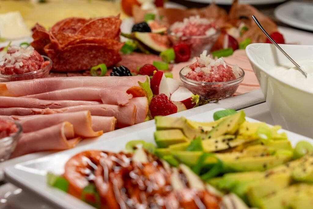 A variety of food items including meats, fruits, and dips.