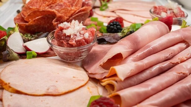 A variety of meats including sliced ham, prosciutto, and other deli items, accompanied by fresh fruits and vegetables. - Hotel am Marschiertor by ANS (Aachen)