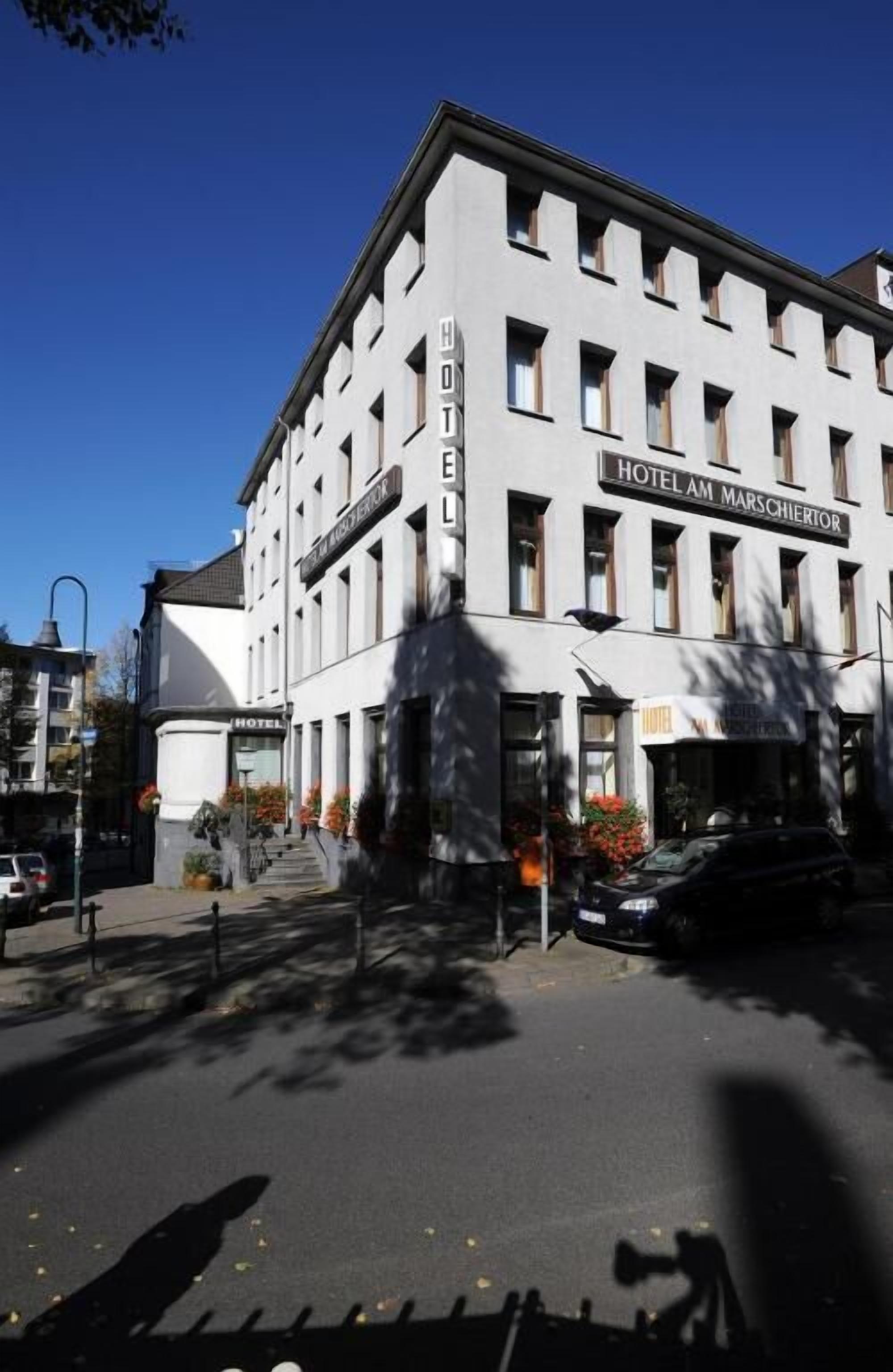 A multi-story hotel with a classic architectural style, featuring a prominent sign reading "HOTEL AM MARCHIERTOR".
