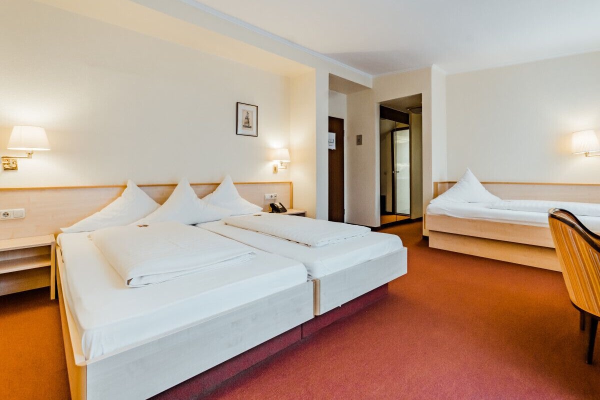 Una habitación de hotel con dos camas, una silla y un escritorio.