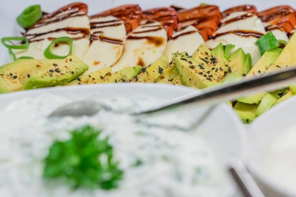 A plate of food with avocado slices, a creamy sauce, and a drizzle of sauce on top.