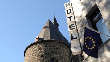 Un letrero de hotel con la palabra 'HOTEL' y 'AM MARSCHIER TOR' escritas, y la bandera de la Unión Europea.