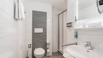 Une salle de bain moderne équipée de toilettes, d’une douche et d’un lavabo.