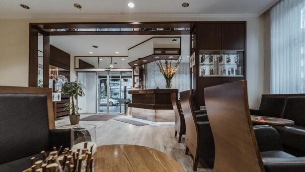 Un moderno vestíbulo de hotel con mostrador de recepción, zona de estar y vistas a la calle.