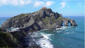 Una isla escarpada con un camino estrecho que lleva a un edificio de techo rojo en la cima.