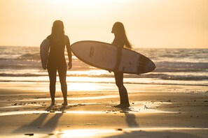 Two people holding surfboards on a beach at sunset. - Moana Eco Surf House - Hostel (Sopelana)