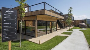 Un edificio moderno con recepción, escuela de surf y habitaciones numeradas del 01 al 23.