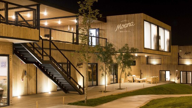 Un edificio moderno con fachada de madera, una escalera y una zona de estar al aire libre.