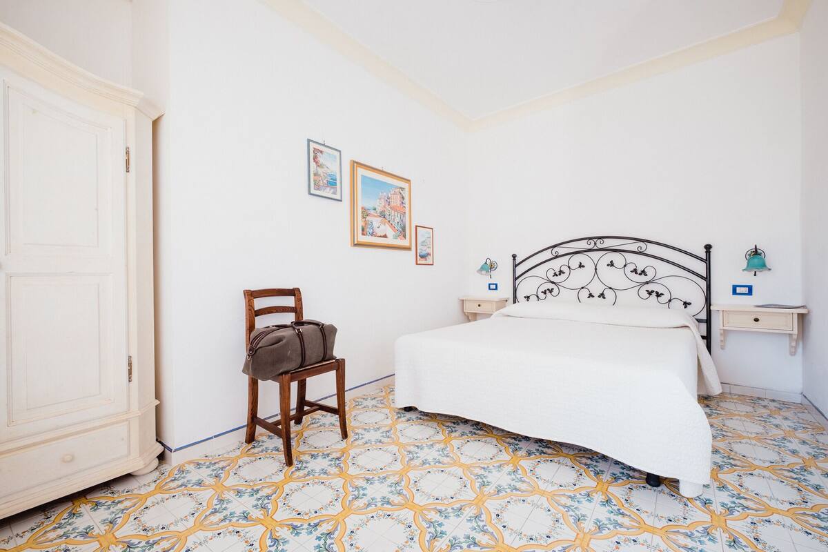 Un dormitorio con una cama, una silla, una mesita de noche y un aparador.