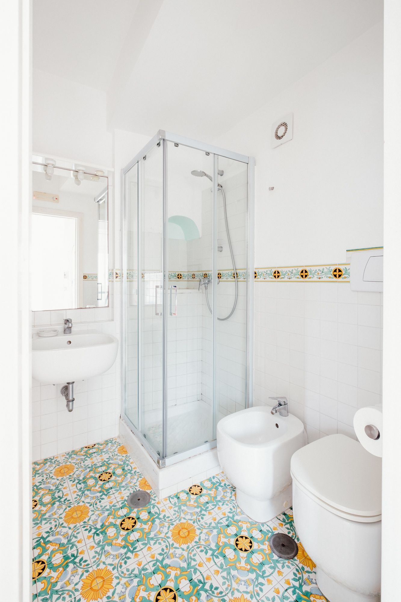 A bathroom with a glass-enclosed shower, a sink, and a toilet.