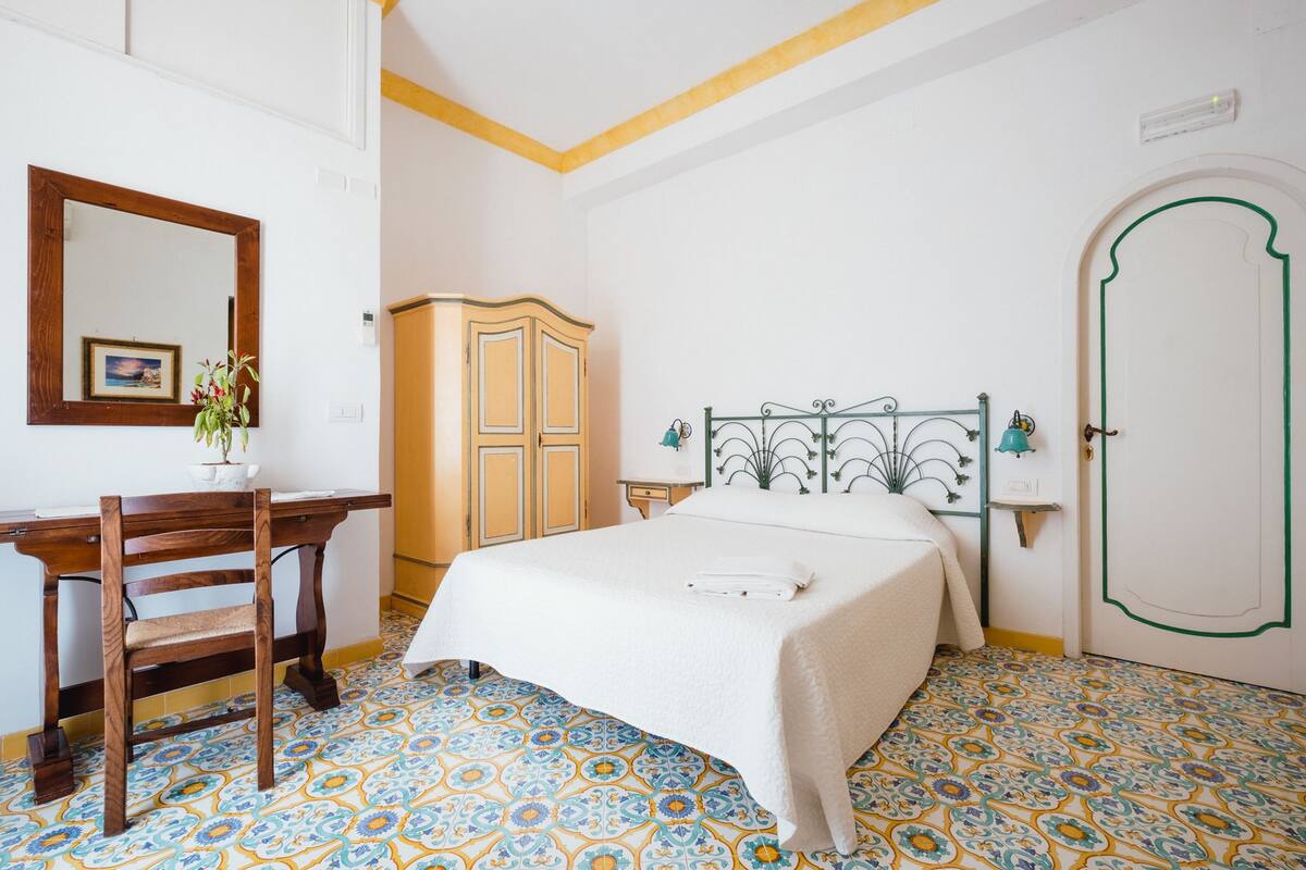 Un dormitorio con una cama, un escritorio, una silla, un armario y una puerta.