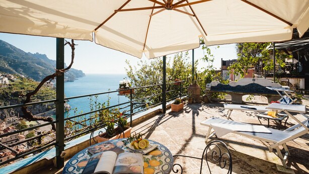 A terrace with a view of the sea, outdoor furniture, and potted plants. - Orto Paradiso (Minori)