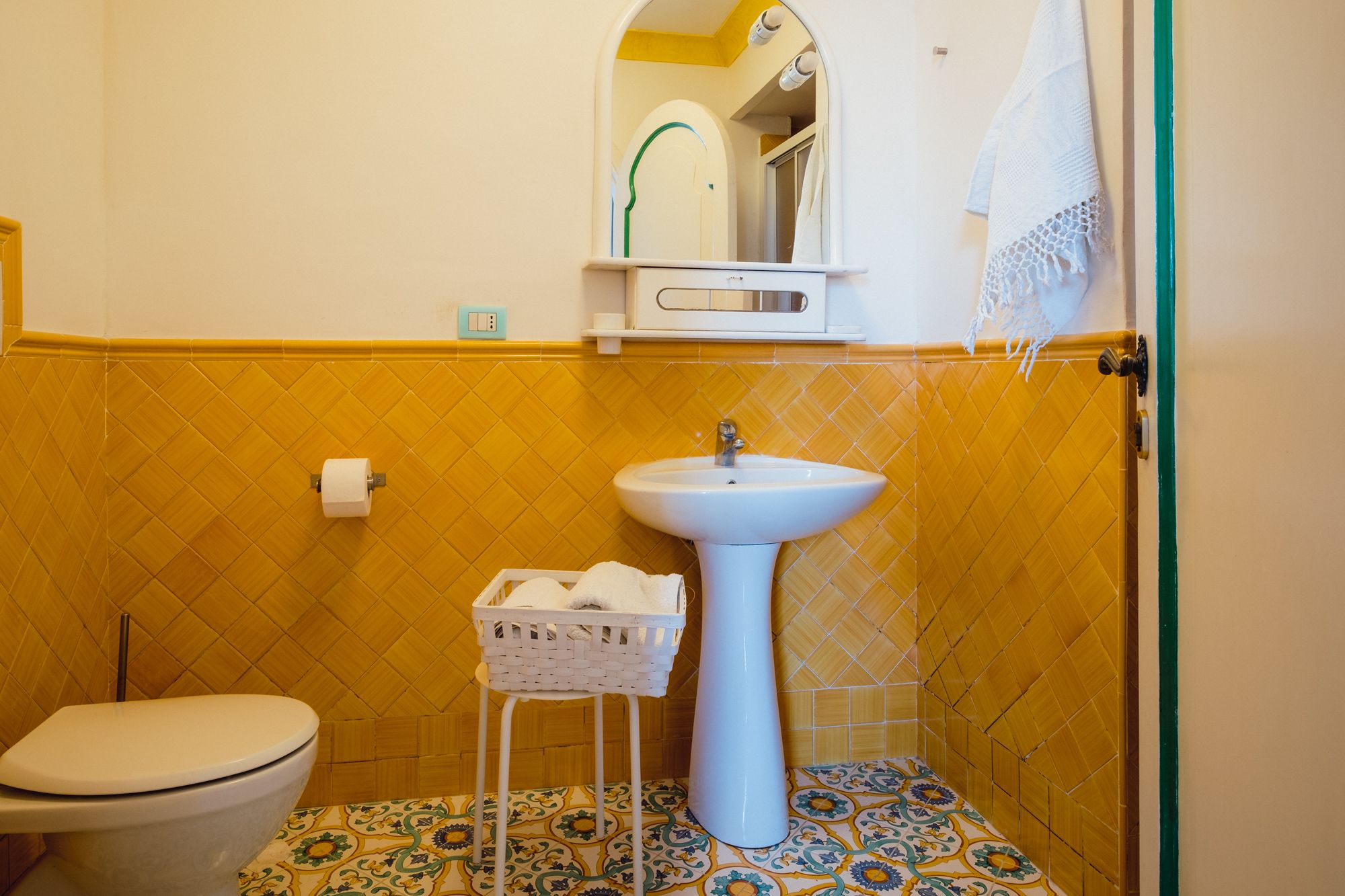 A bathroom with a white sink, toilet, and a small wicker basket.