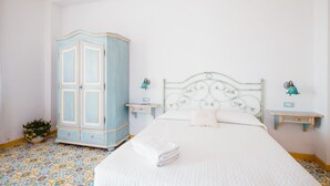 A bedroom with a bed, a wardrobe, two bedside tables, and a wall-mounted lamp. - Orto Paradiso (Minori)