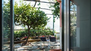 A patio area with a view of a tree and a body of water. - Orto Paradiso (Minori)