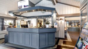Un espace cuisine moderne doté d’un îlot central, d’appareils électroménagers intégrés et d’une étagère où sont exposés des magazines.