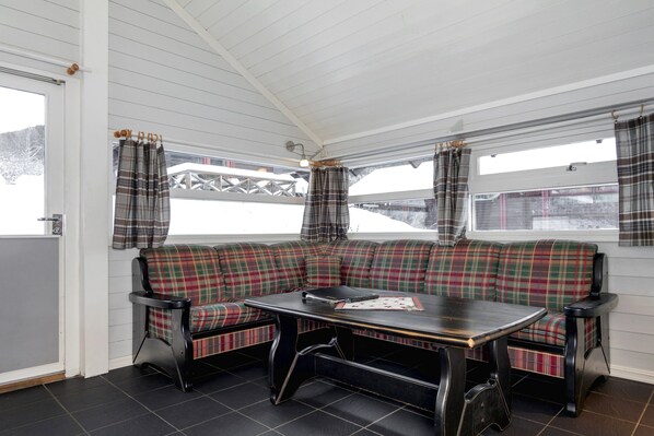 A cozy room with a plaid sofa, a small table, and a window with plaid curtains. - Gol Campingsenter (Gol)