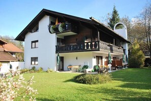 A two-story house with a balcony, a covered porch, and a small garden area. - Florianshof (Garmisch-Partenkirchen)