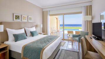 Una habitación de hotel con cama, escritorio, televisor y vista al océano.