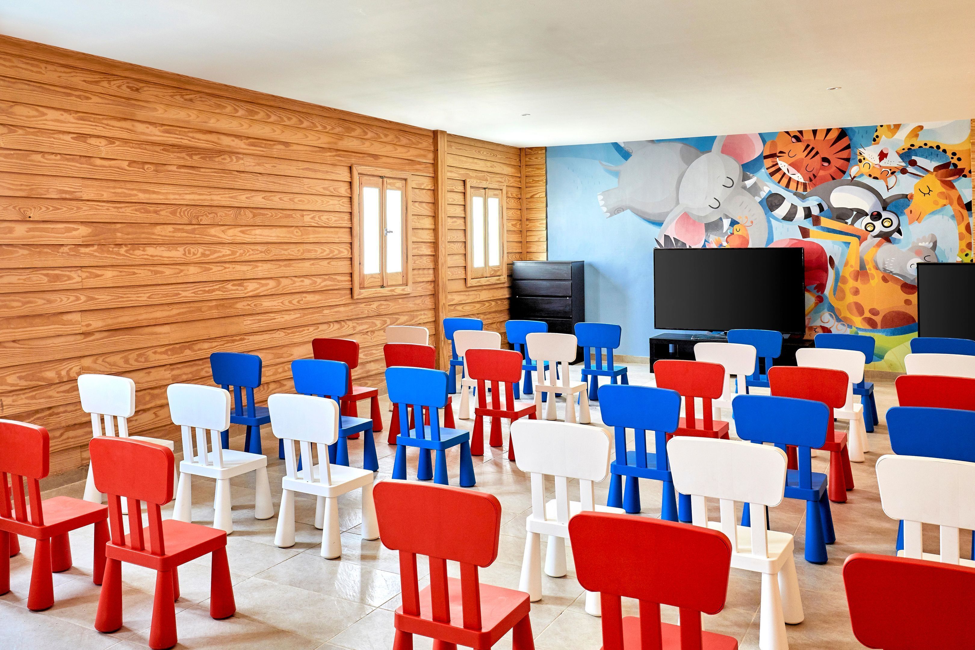 A room with wooden walls, a large mural, and rows of colorful chairs.