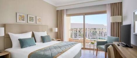 A hotel room with a bed, a desk, a chair, a TV, and a balcony with a view.