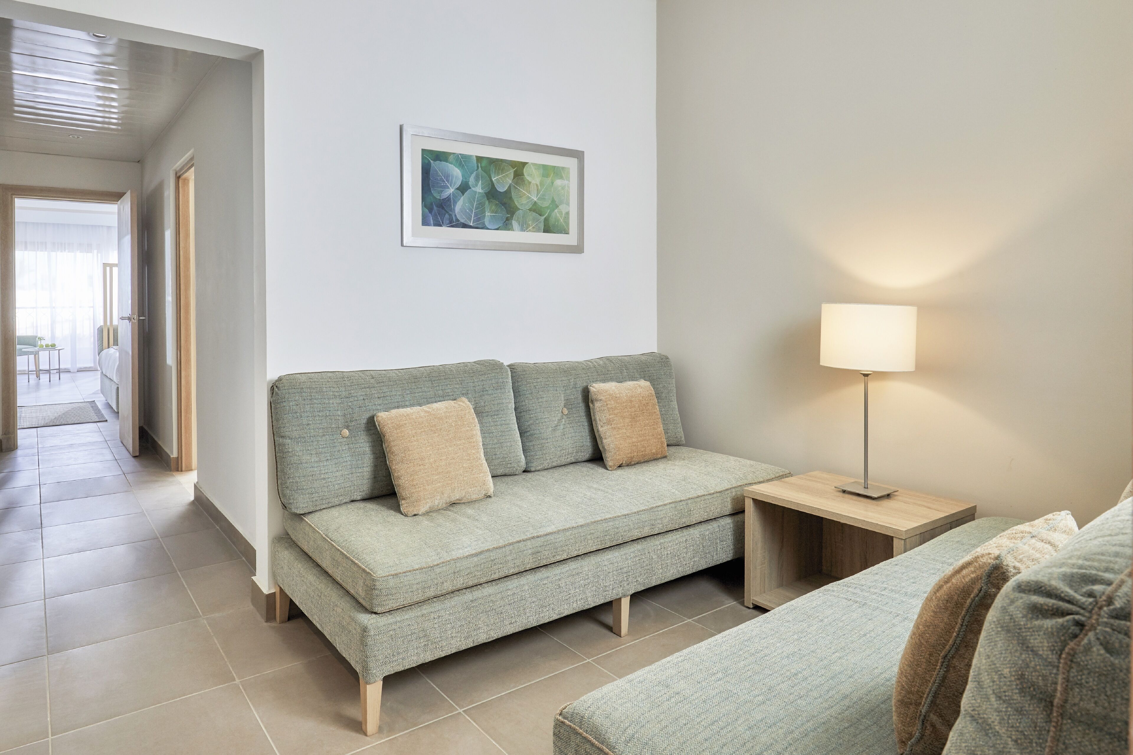 Een moderne woonkamer met een bank, een bijzettafeltje en een lamp.
