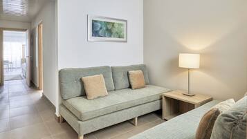 Een moderne woonkamer met een bank, een bijzettafeltje en een lamp.