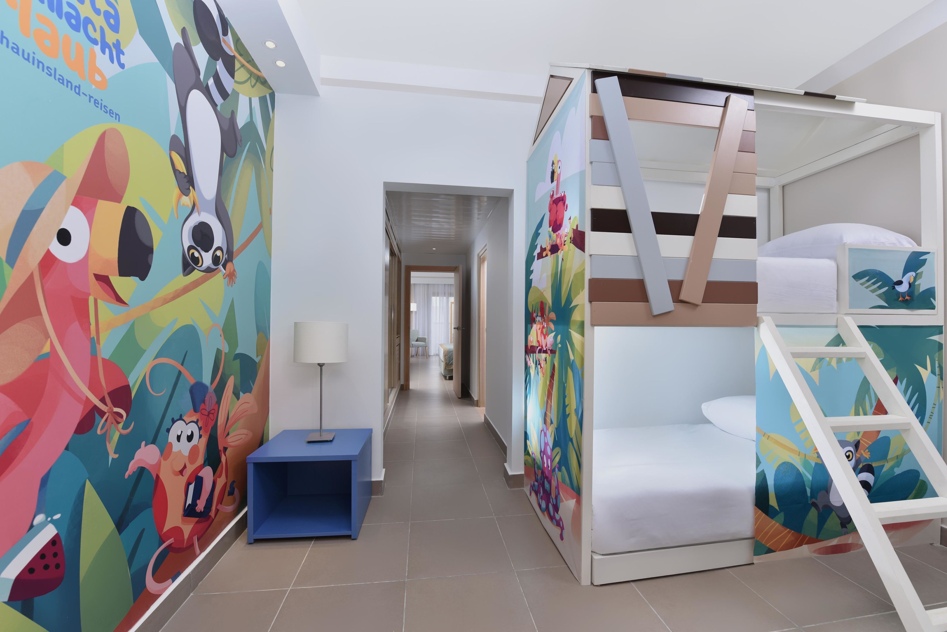 A children's room with a bunk bed, colorful murals, a small desk, and a lamp.