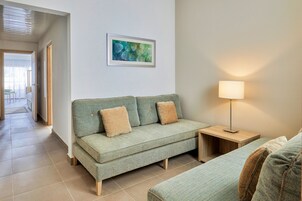 Una sala de estar moderna con un sofá, una mesita auxiliar y una lámpara.