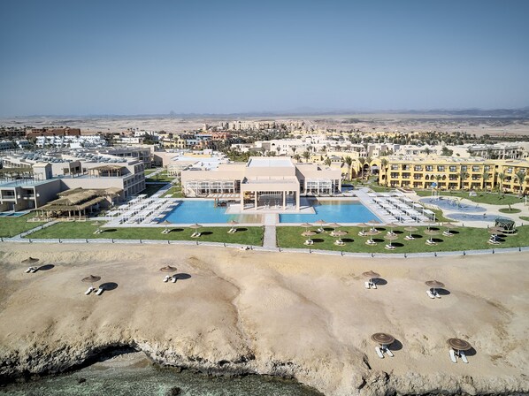 Resort com piscina central, vários edifícios e paisagem desértica.
