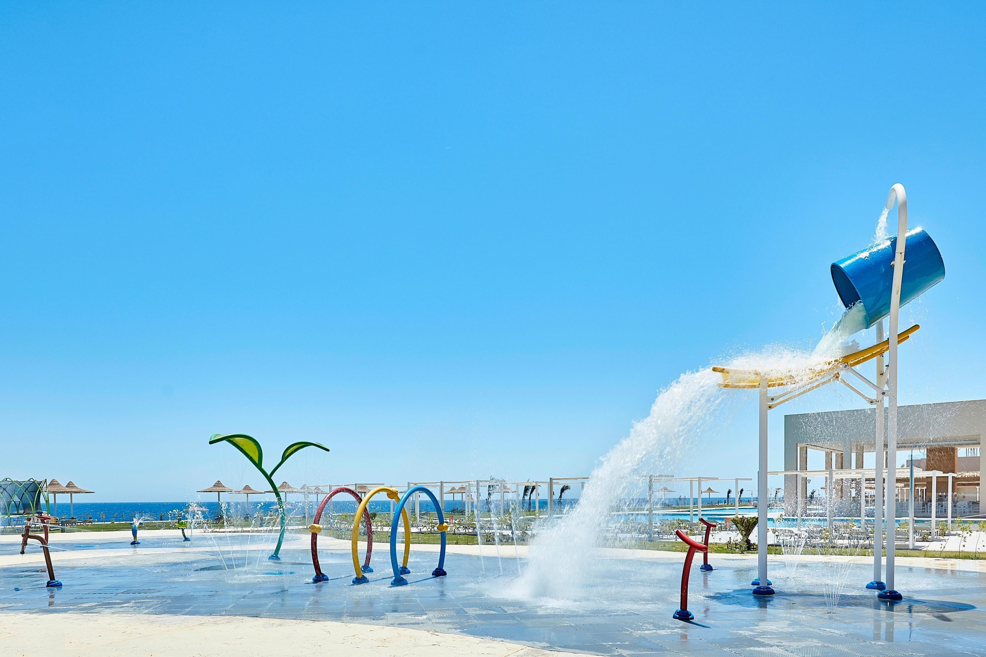 A water play area with multiple water jets and a blue bucket fountain.