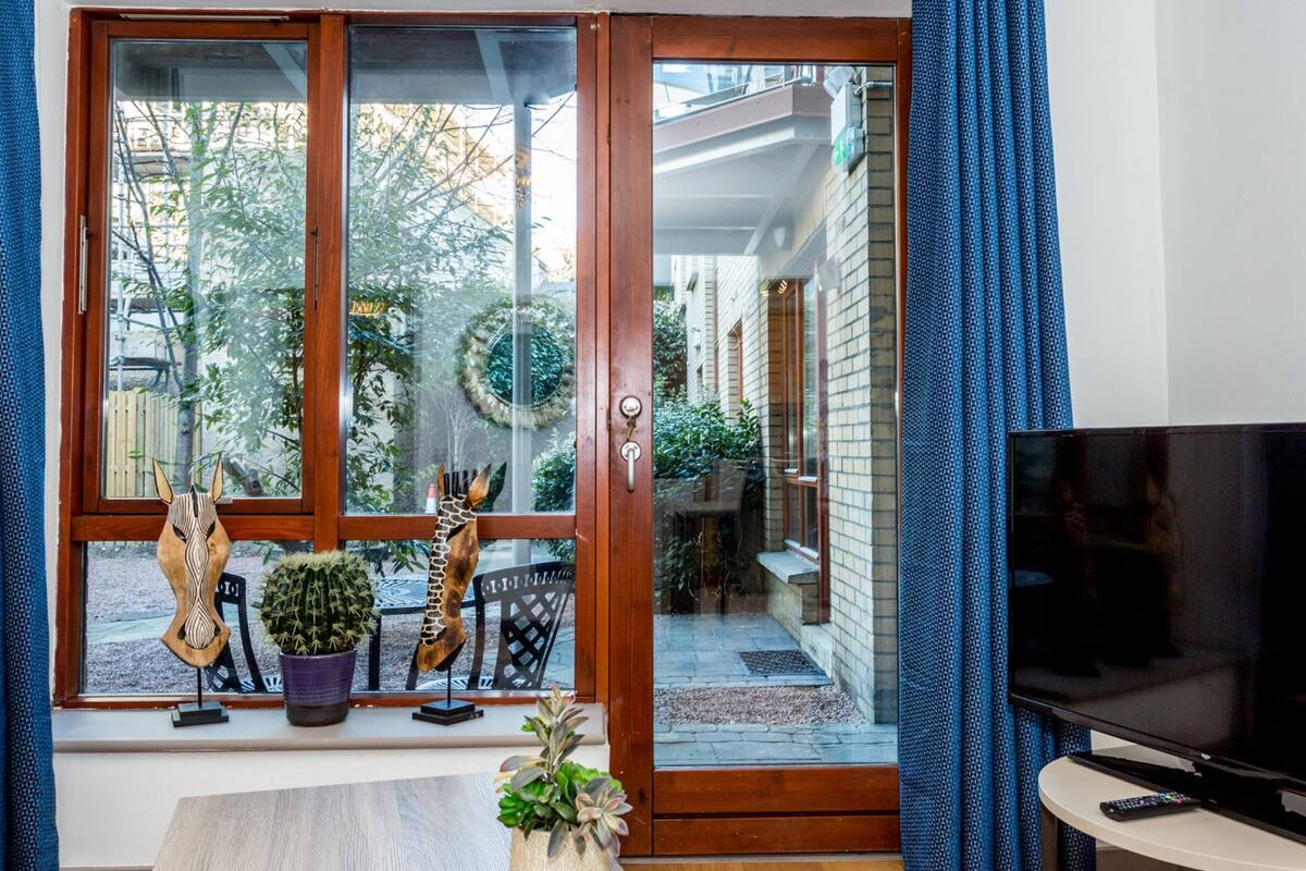 A living room with a sliding glass door leading to a balcony, a television, and a sofa.