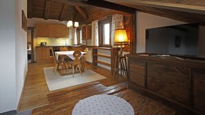Ett mysigt kök med träskåp, ett matbord med stolar, en tv och en öppen spis.