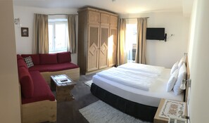 Ein Zimmer mit einem Bett, einem roten Sofa, einem Holzschrank und einem Fernseher.