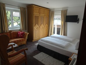 Ein Schlafzimmer mit einem Bett, einem Holzschrank, einer Couch und einem Sessel.
