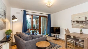 A modern living room with a sofa, coffee table, TV, and dining area. - Thomas Street Apartments (Dublin)