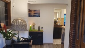 Un couloir avec un comptoir d’accueil, une lampe et un tableau accroché au mur.