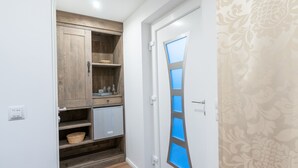 Un couloir avec un meuble en bois, un petit réfrigérateur et un mur orné d’un motif.
