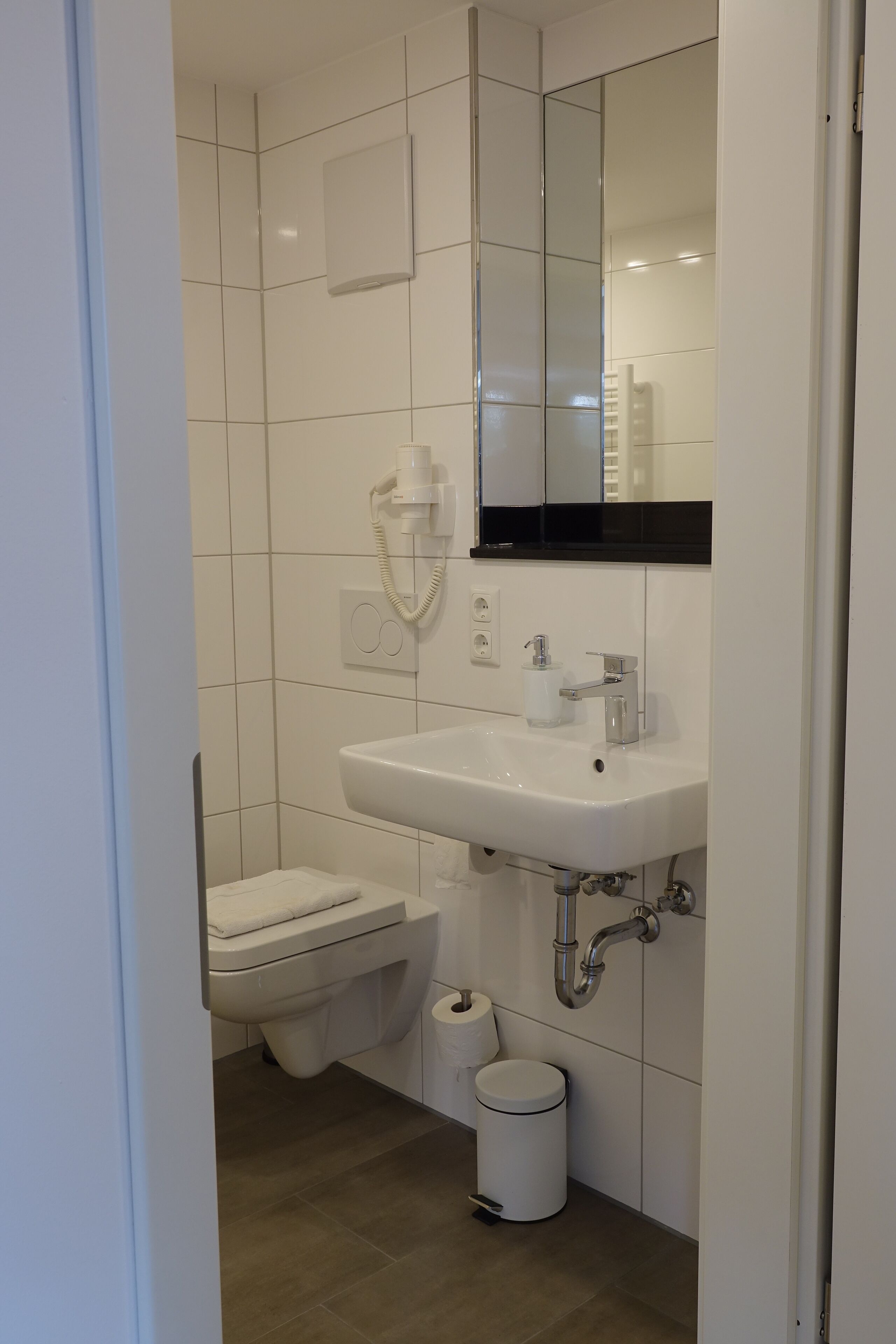 A small, clean bathroom with a white sink, toilet, and a mirror above the sink.